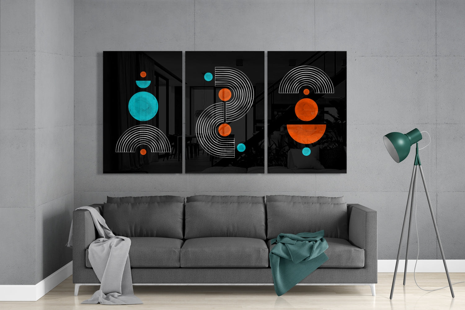Abstract wall art on a gray wall above a gray sofa with a green lamp.